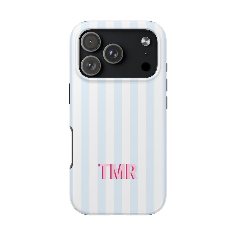 May include: A smartphone case featuring a vertical light blue and white striped pattern. The back of the case displays the letters TMR in a bold pink font centered near the bottom. The camera module area is black with three circular lenses.