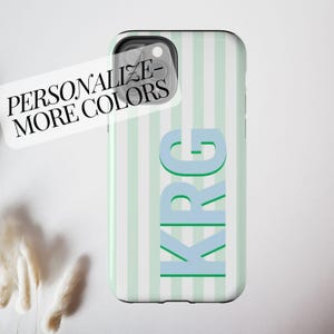 May include: A phone case with a vertical striped pattern in light green and white. The initials "KRG" are displayed in a light blue color. The text "PERSONALIZE - MORE COLORS" is on a white sticker.