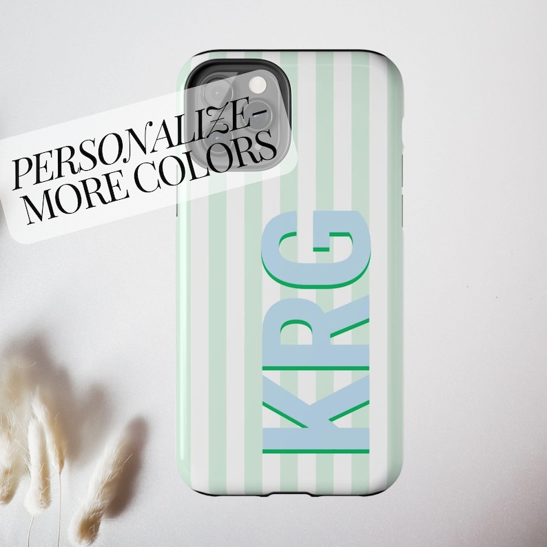 Custom monogram iPhone case featuring light pink and white vertical stripes in a preppy retro design, with bold shadow initials ‘AKL’ printed vertically for a modern personalized touch. This stylish tough phone cover is perfect for summer, beachy vibes, or as a cute gift idea for her. Available for iPhone 16, 15, 14, 13 models and more, with the option to personalize colors and letters. Great for those who love unique, aesthetic accessories that protect your phone while showing off your initials