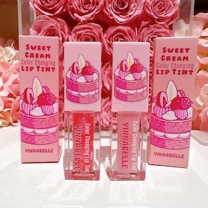 K&ouml;nnte beinhalten: Drei rosa und wei&szlig;e Lippenbalsame mit einem Kuchen-Design und dem Text "Sweet Cream Color Changing Lip Tint" und "Vinnabelle".