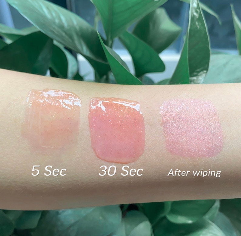 K&ouml;nnte beinhalten: Drei Lippgloss-Swatches auf dem Arm einer Person. Der erste Swatch ist klar und mit "5 Sec" beschriftet. Der zweite Swatch ist rosa und mit "30 Sec" beschriftet. Der dritte Swatch ist hellrosa und mit "Nach dem Abwischen" beschriftet.
