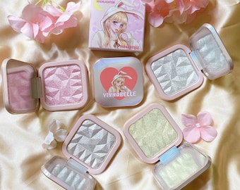 May include: Five pink and white compact makeup palettes with a holographic finish. Each palette has a different colour and features a cartoon illustration of a girl with bunny ears. The packaging says "Kawaii Girl Highlighter" and "Yinnabelle".