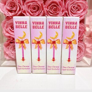 May include: Four bottles of liquid eyeshadow with a pink and white label. The label features a cartoon image of a wand with a crescent moon and a red bow. The text on the label reads "Vinna Belle Duo Chrome Liquid Eyeshadow".