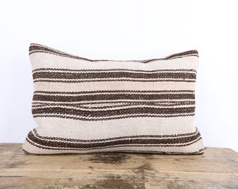 May include: A brown and white striped throw pillow with a woven texture.