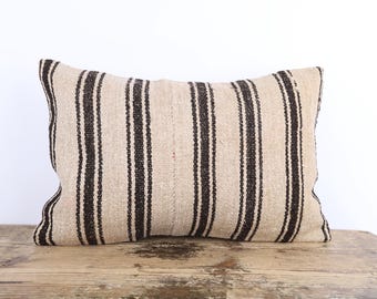 May include: A beige and black striped throw pillow with a woven texture. The pillow is made of a natural fabric and has a rustic look.