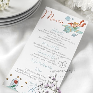 Puede incluir: Una tarjeta de men&uacute; blanca con una ilustraci&oacute;n azul y naranja de un zorro y un ni&ntilde;o volando en un avi&oacute;n. La tarjeta de men&uacute; enumera los platos para una recepci&oacute;n de boda, incluyendo antipasto, primo piatto, secondo piatto y postre. El texto en la tarjeta est&aacute; en italiano.