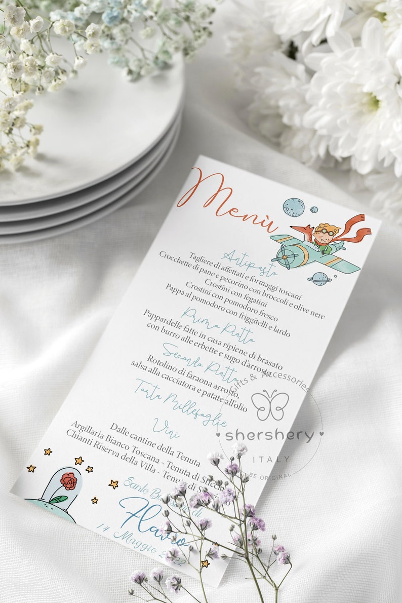 Puede incluir: Una tarjeta de men&uacute; blanca con una ilustraci&oacute;n azul y naranja de un zorro y un ni&ntilde;o volando en un avi&oacute;n. La tarjeta de men&uacute; enumera los platos para una recepci&oacute;n de boda, incluyendo antipasto, primo piatto, secondo piatto y postre. El texto en la tarjeta est&aacute; en italiano.