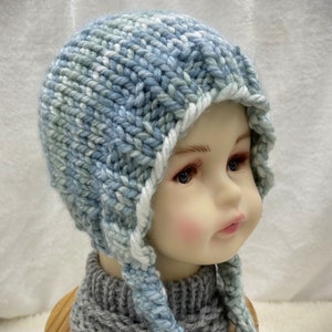 May include: A blue and white knitted baby hat with long ties. The hat has a white brim and is made with a chunky yarn.