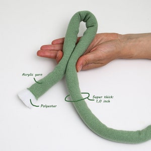 May include: A close-up of a green yarn rope, approximately 1 inch thick. The rope is made of acrylic yarn with a polyester core.