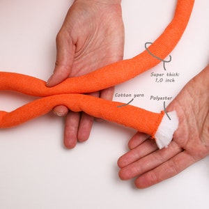 May include: Close-up of a thick orange rope made of cotton yarn and polyester. The rope is 1.0 inch thick.