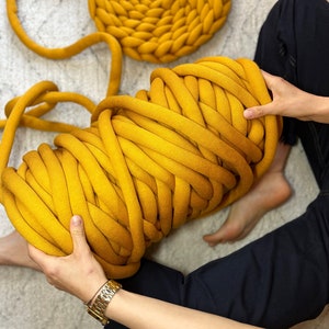 May include: A large ball of thick, yellow yarn. The yarn is made of soft, chunky fibers and is perfect for knitting or crocheting.