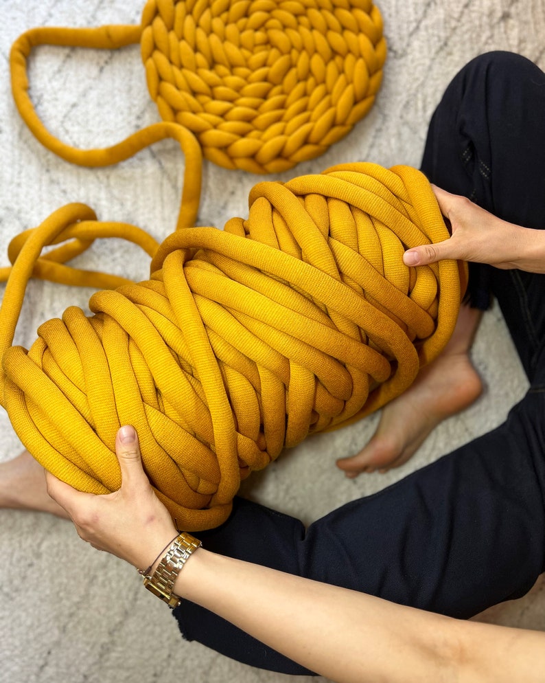 May include: A large ball of thick, yellow yarn. The yarn is made of soft, chunky fibers and is perfect for knitting or crocheting.