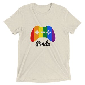 May include: A light beige t-shirt with a rainbow colored video game controller graphic and the word "Pride" in black text.