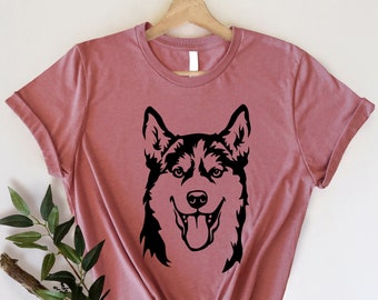 May include: A mauve t-shirt with a black silhouette of a husky dog's head.