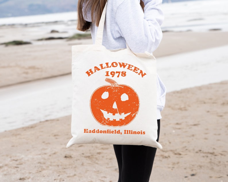 May include: A white tote bag with an orange pumpkin and the text "Halloween 1978 Haddonfield, Illinois".