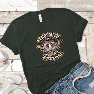 May include: A dark green t-shirt with a leopard print design featuring the text "Aerosmith" and "Authentic Rock & Roll".