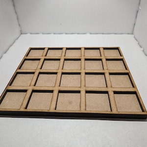 May include: A flat, square wooden grid tray featuring a four-by-four arrangement of sixteen open square compartments. The tray is constructed from light brown, unfinished wood with a smooth, uniform texture and dark, laser-cut edges.