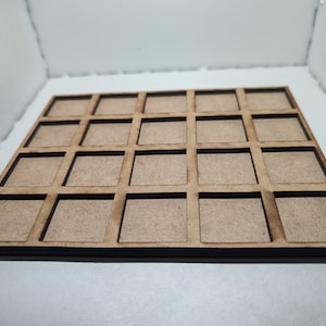 May include: A square wooden grid tray featuring twenty individual square compartments arranged in a four-by-five layout. The tray is constructed from light brown, unfinished wood with dark, laser-cut edges defining each open square section.