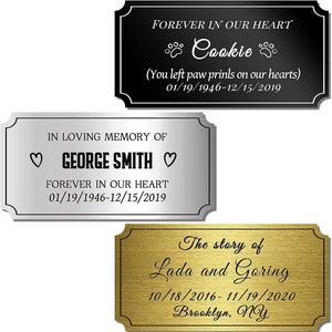 May include: Three silver and gold memorial plaques with black lettering. The top plaque reads "FOREVER IN OUR HEART Cookie (You left paw prints on our hearts) 01/19/1946-12/15/2019". The middle plaque reads "IN LOVING MEMORY OF ♡GEORGE SMITH♡ FOREVER IN OUR HEART 01/19/1946-12/15/2019". The bottom plaque reads "The story of Lada and Goring 10/18/2016-11/19/2020 Brooklyn, NY".