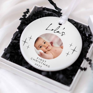 Könnte beinhalten: Weißer Keramik-Weihnachtsbaumschmuck mit einem Foto eines Babys und dem Text "Lola's First Christmas 2023".