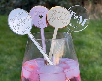 May include: Three round acrylic drink stirrers with personalized text. The stirrers are in a glass of pink drink with ice. The text on the stirrers reads "Mr & Mrs Bedding 24.07.22", "Emma & Sid", and "Mr & Mrs Birchall 20.6.22 T&M".