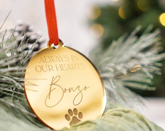 May include: Gold-colored round ornament with the text "Always in our hearts" and the name "Bonzo" written in cursive. A paw print is below the name.