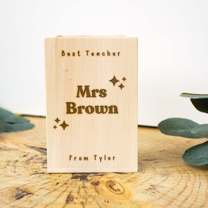 May include: A wooden box with the text "Best Teacher" and "Mrs Brown" engraved on it. The box also has small stars and the text "From Tyler" engraved on it.