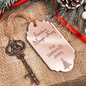 May include: A rose gold key with a Santa Claus design and a tag that reads "Santa's Magic Key For Matthew & Jenny" with a small Christmas tree design.