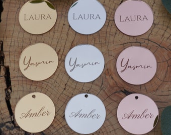 May include: Nine round, mirrored acrylic tags with names printed on them. The tags are in three colors: gold, silver, and rose gold. The names on the tags are Laura, Yasmin, and Amber.