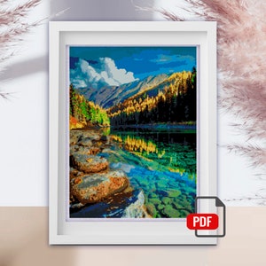 Può includere: Una stampa incorniciata di un paesaggio panoramico con un lago circondato da montagne e alberi. Il lago è di un colore blu e verde vibrante, e le montagne sono ricoperte di alberi verdi lussureggianti. Il cielo è di un blu brillante con nuvole bianche.