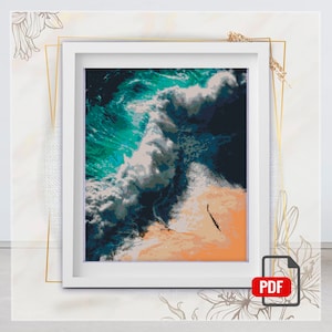 May include: An aerial view of a large wave crashing on a sandy beach. The wave is a mix of white foam and turquoise blue water. The beach is a light orange color.
