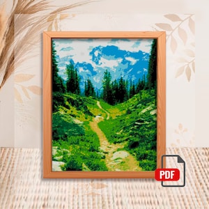 May include: A framed cross-stitch pattern depicting a mountain landscape with a winding path leading through a forest. The sky is blue with white clouds and the mountains are a light blue colour. The forest is green and the path is brown.