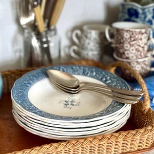 Peut inclure: Une pile d'assiettes en céramique à motifs bleus et blancs avec une cuillère en argent sur le dessus. Les assiettes sont disposées dans un panier en osier.