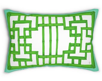 Può includere: Un cuscino rettangolare con un motivo geometrico verde e bianco. Il motivo ricorda un reticolo di bambù. Il cuscino ha un bordo blu chiaro.