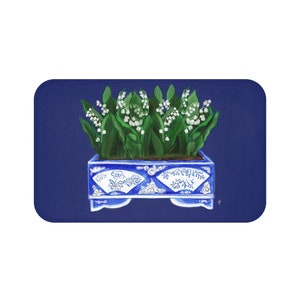 May include: A blue and white porcelain planter with a decorative design filled with a bouquet of white lily of the valley flowers.