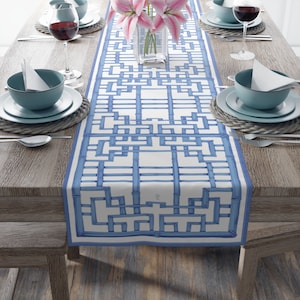 May include: A blue and white geometric table runner with a bamboo design. The runner is on a wooden table with two place settings on each side.