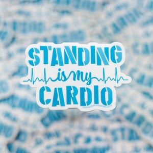 Op de afbeelding: Een witte sticker met de tekst "STANDING is my CARDIO" in blauwe sjabloonletters, met een blauwe hartslaglijn. De sticker bevat ook het websiteadres rosewatercreative.com.