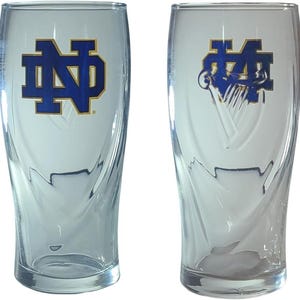 May include: Two clear glass pint glasses with a blue and gold logo. The logo features the letters "ND" intertwined. The glasses have a curved design and are suitable for beverages.