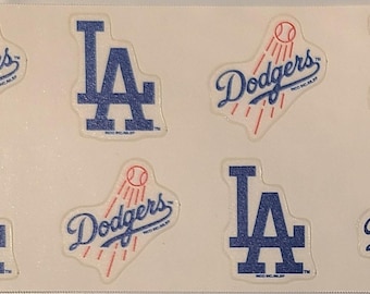 May include: Sheet of stickers featuring the Los Angeles Dodgers logo and the team's "LA" emblem. The stickers are in blue and white, with a baseball graphic. The word "Dodgers" is written in cursive.