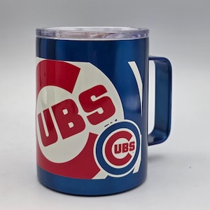 May include: A blue travel mug with the Chicago Cubs logo in red and white. The mug has a handle and a clear lid. The Cubs logo is displayed on the front of the mug.