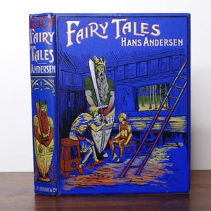 Könnte beinhalten: Ein blaues Vintage-Hardcover-Buch mit dem Titel "Fairy Tales" von Hans Andersen. Das Cover zeigt Illustrationen von Figuren und einer Leiter. Der Buchrücken zeigt ebenfalls den Titel und den Autor.