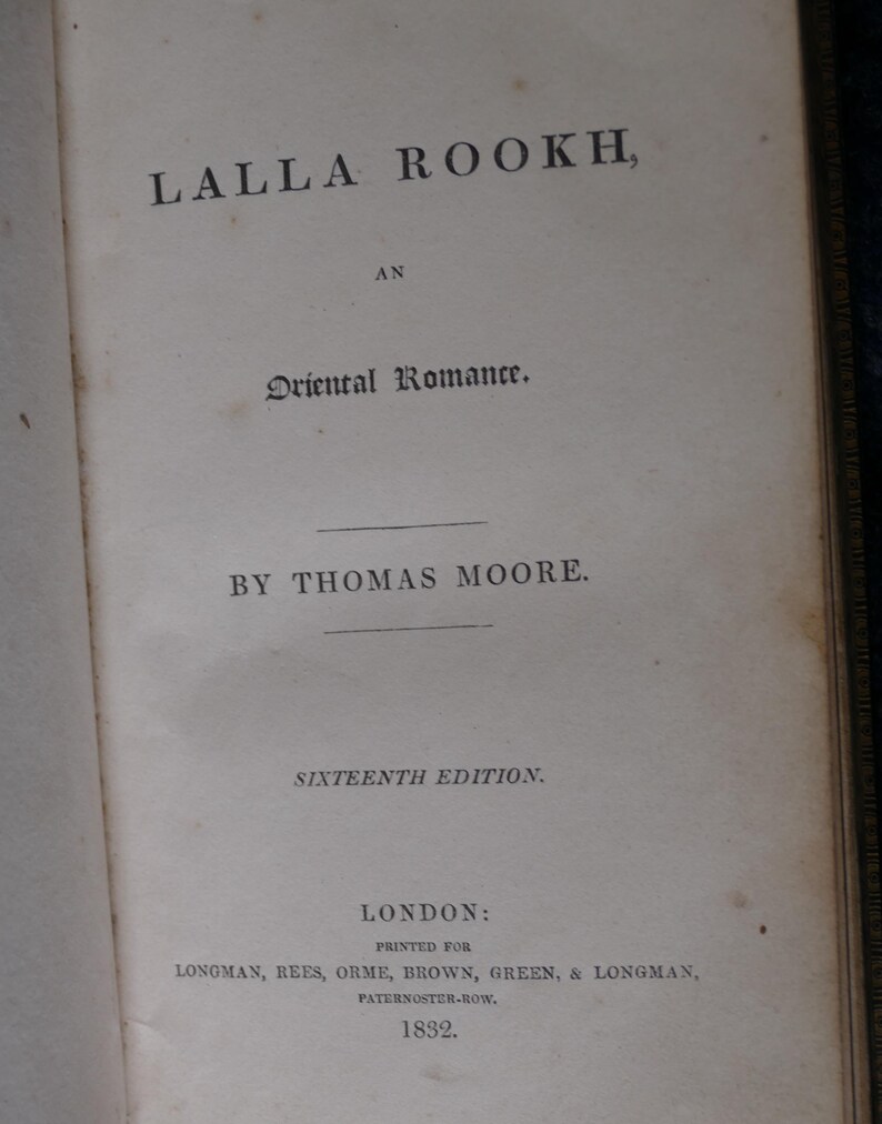 May include: Open book page with the title "LALLA ROOKH, AN Oriental Romance" by Thomas Moore. The text is in black ink on aged, off-white paper. The book is a sixteenth edition, printed in London in 1832.