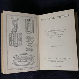 May include: An open book titled "Practical Physics" with detailed diagrams and text. The left page features technical illustrations of measuring instruments. The right page displays the title, author information, and publisher details. Published by Longmans, Green, and Co.