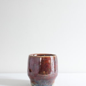 May include: A white ceramic mug with a black handle and the text "But First, Coffee" in a black, bold font. The mug is sitting on a wooden surface. The mug is approximately 4 inches tall.