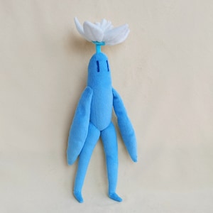 May include: A blue plush toy with a white flower on its head. The toy has long arms and legs and a simple face.