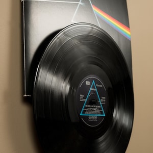 May include: A black vinyl record with a blue and white triangle design on the label. The record is titled "The Dark Side of the Moon" by Pink Floyd.