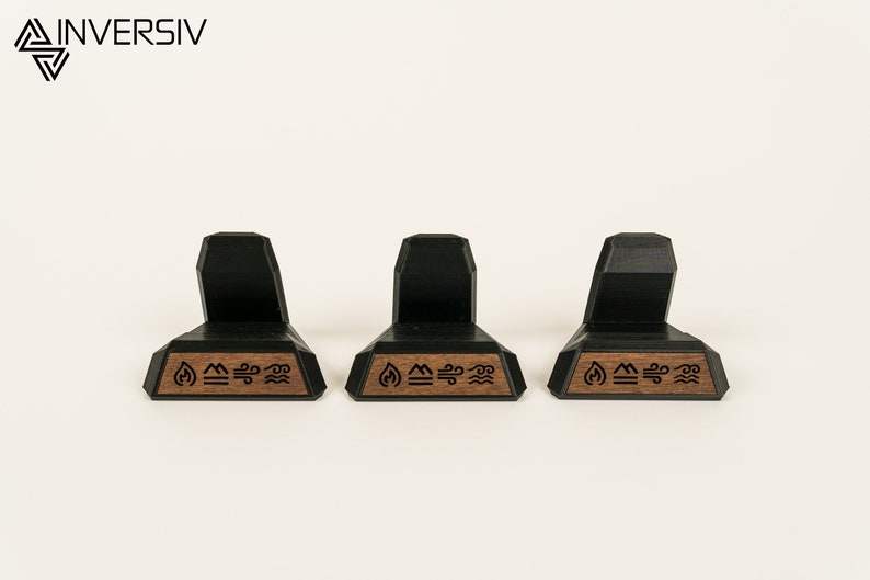 May include: Three black and brown wooden display stands with a geometric design. Each stand has a small wooden plaque with the symbols for fire, earth, air, and water.