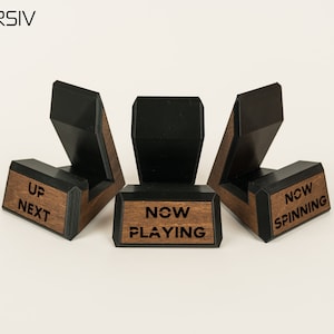 May include: Three black and wood record holders with the words "Up Next", "Now Playing", and "Now Spinning" engraved on them.