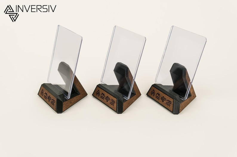 May include: Three wooden display stands with clear acrylic inserts. Each stand features a triangular base with a black top and a brown wood bottom. The base is engraved with the word "INVERSIV" and a symbol.