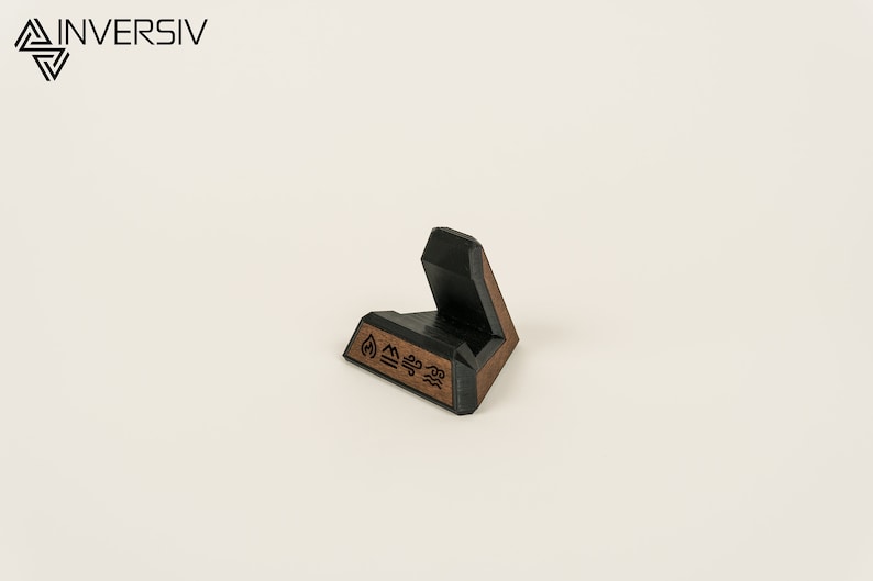 May include: A black and brown wooden phone stand with a geometric design and the symbols for fire, earth, air, and water.